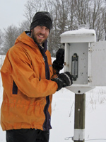 Graduate student checks data station in snowy field